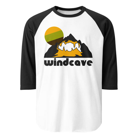 A three quarter sleeve white and black raglan style Wind Cave t-shirt with an image of a large black mountain with yellow caves inside and a white hiking trail, referencing how people can hike through the cave system, and a green/yellow/brown circular sun in the backdrop. Wind Cave National Park is one of the largest and oldest cave systems in the entire world and the first cave that was also a national park. 