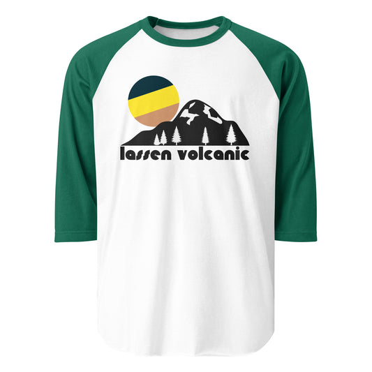 A 3/4 sleeve retro raglan style white and kelly green shirt that includes the image of a striped and colorful sun setting over a large mountain complete with fir trees. Says "Lassen Volcanic" in reference to Lassen Volcanic National Park, home to Lassen peak - the largest plug dome volcano on the globe - and various other active volcanoes, the entire landscape defined by volcanism, and the area popular for hydrothermal sites such as Bumpass Hell and large expanses such as the Devastated Area. 