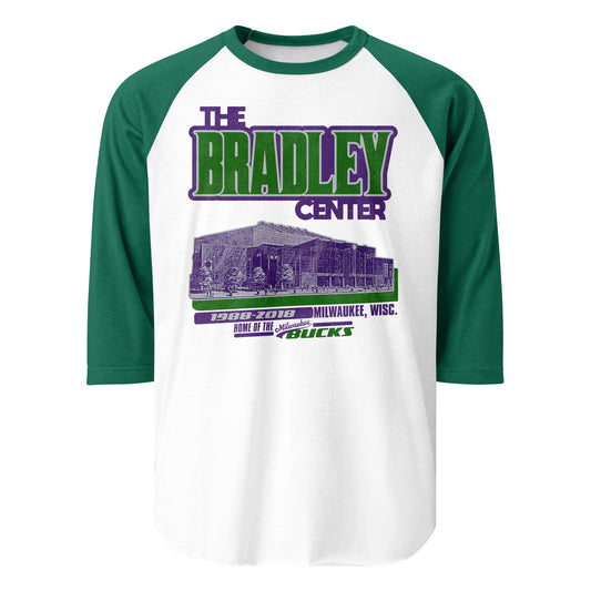 A 3/4 sleeve raglan style green and white retro shirt for The Bradley Center in Milwaukee, Wisc., Home of the Milwaukee Bucks from 1988-2018. Image of the stadium from the street in purple with a green shadow, representing the Bucks colors. 