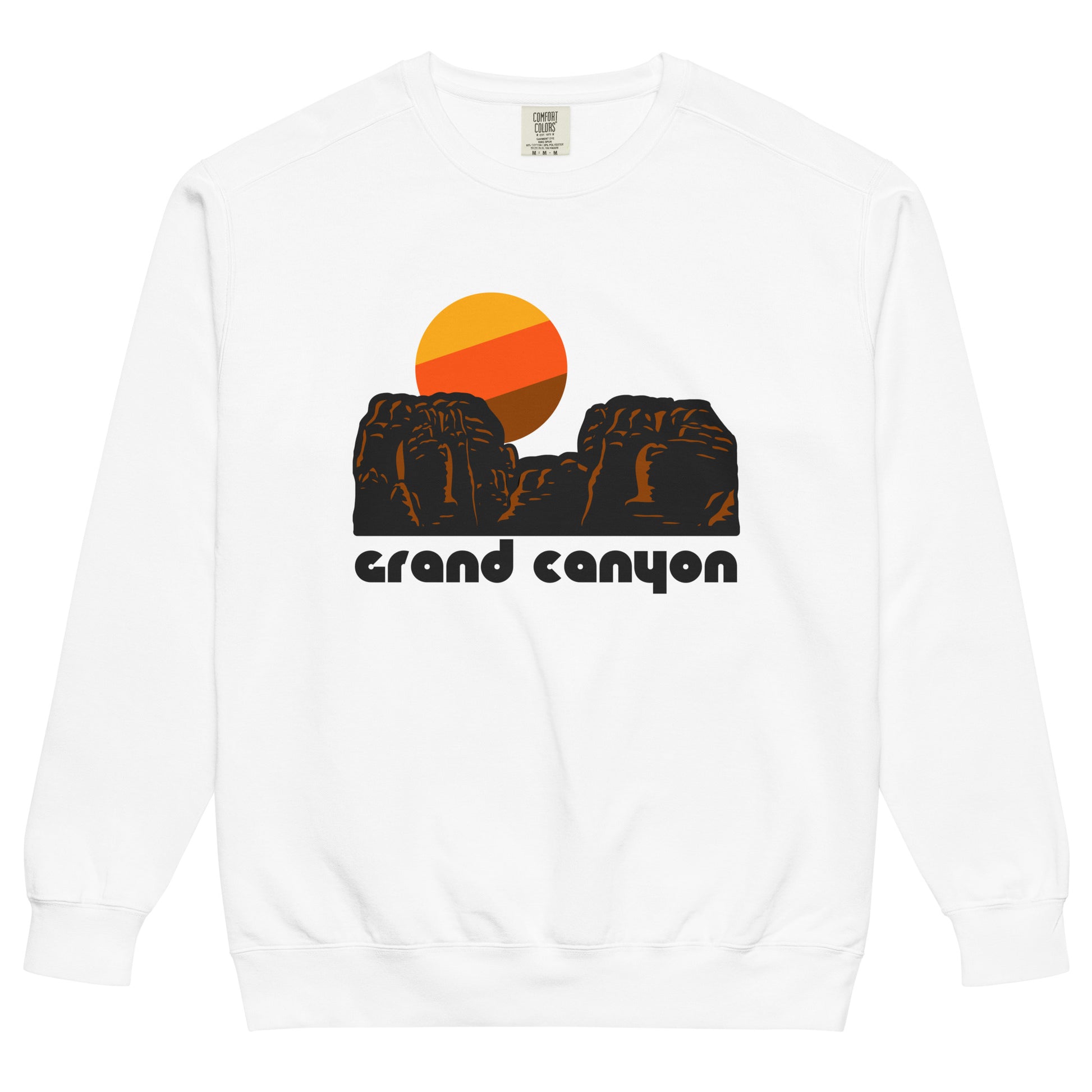 A white crew neck 80s style souvenir sweatshirt with the image of a red rock landscape, a yellow, orange, and brown sun setting in the distance. The sweatshirt says 'Grand Canyon', referencing the world famous national park, a perfect destination for tourists and adventurers, with opportunities to raft on the Colorado River, ride on mules, hiking trails down the canyon, and stunning viewpoints. 