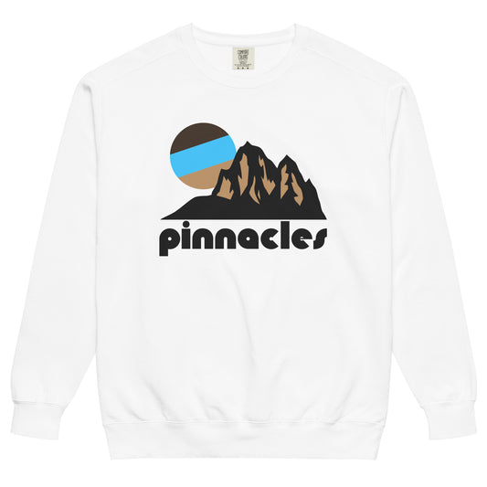 An 80s style, souvenir 'pinnacles' crew neck white sweatshirt. Includes the image of a light brown mountainous landscape with a beautiful setting sun in bright blues and browns, referencing Pinnacles National Park in CA, famous for its pinnacles, unique rock formations, and talus caves. 