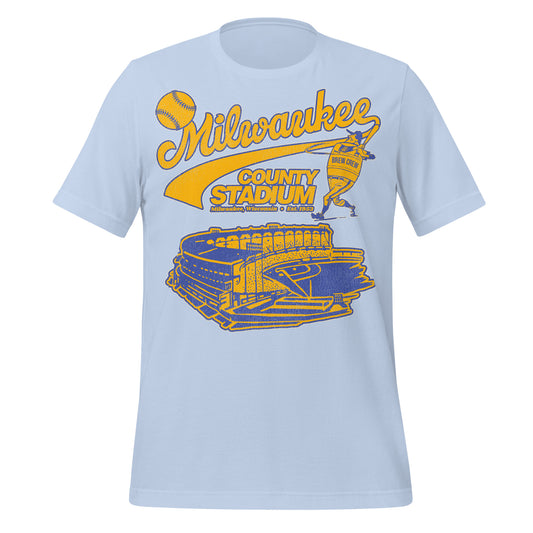 A baby blue 70s style Milwaukee County Stadium t-shirt with an image of a baseball player wearing a "Brew Crew" jersey hitting a baseball over the huge stadium with a baseball diamond in gold and blue. Shirt says "Milwaukee, Wisconsin" and 
"Est. 1953" in reference to the stadium which served as Home of the MKE Braves and later the MKE Brewers. 