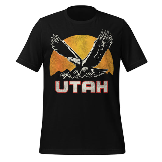 A black colored retro short sleeved t-shirt that says "Utah" with an image of a golden eagle, Utah's state bird of prey, in front of a sun over a mountain range. 
