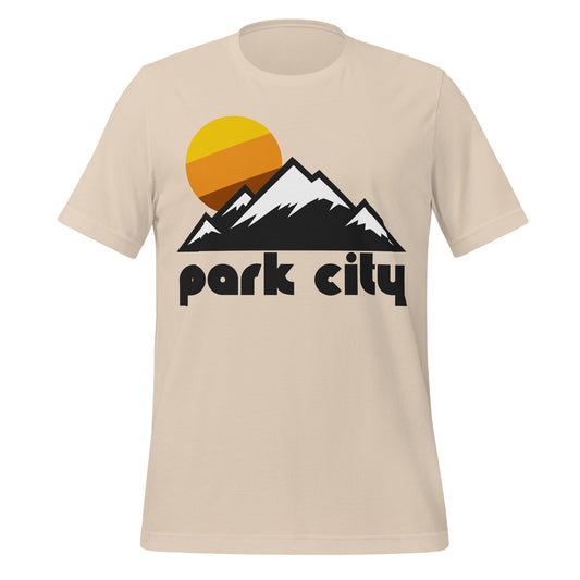 An 80s style souvenir Park City Mountain resort soft cream t-shirt with an image of a mountain range, representing the Wasatch Mountains, and a beautiful tricolored yellow, orange, and brown sun setting. References the skiing, snowboarding, and tubing resort located in Park City, Utah. 