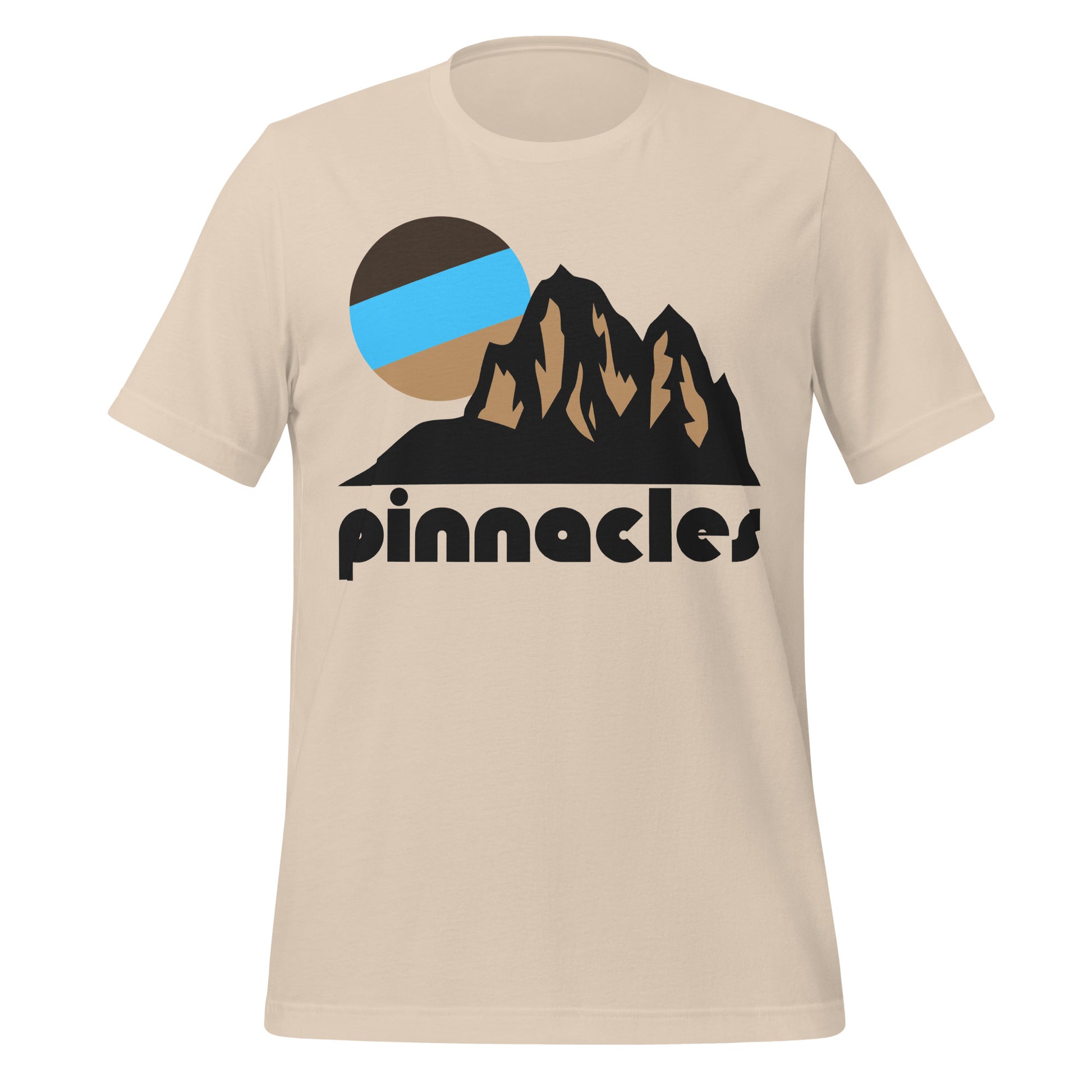 A souvenir Pinnacles National Park soft cream short sleeved t-shirt with the image of stunning rock formations and mountains with a tricolored sun setting in the distance. The shirt says 'pinnacles' in reference to the incredible rock formations  that are unique to the Californian national park, created by volcanic eruption and action millions of years ago. 