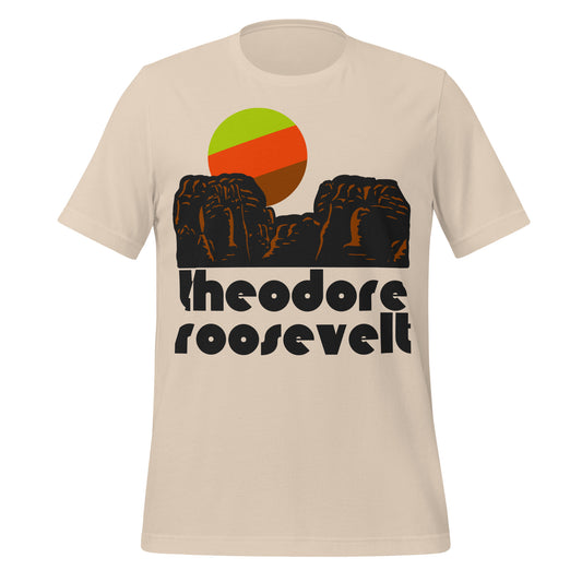 A soft cream vintage souvenirTheodore Roosevelt National Park t-shirt with the image of brownish reddish rock formations and a tricolored sun. The national park, located in the North Dakotan Badlands, is the only in America to be named after one man, due to its influence on Theodore Roosevelt who loved the Little Missouri River Valley. 