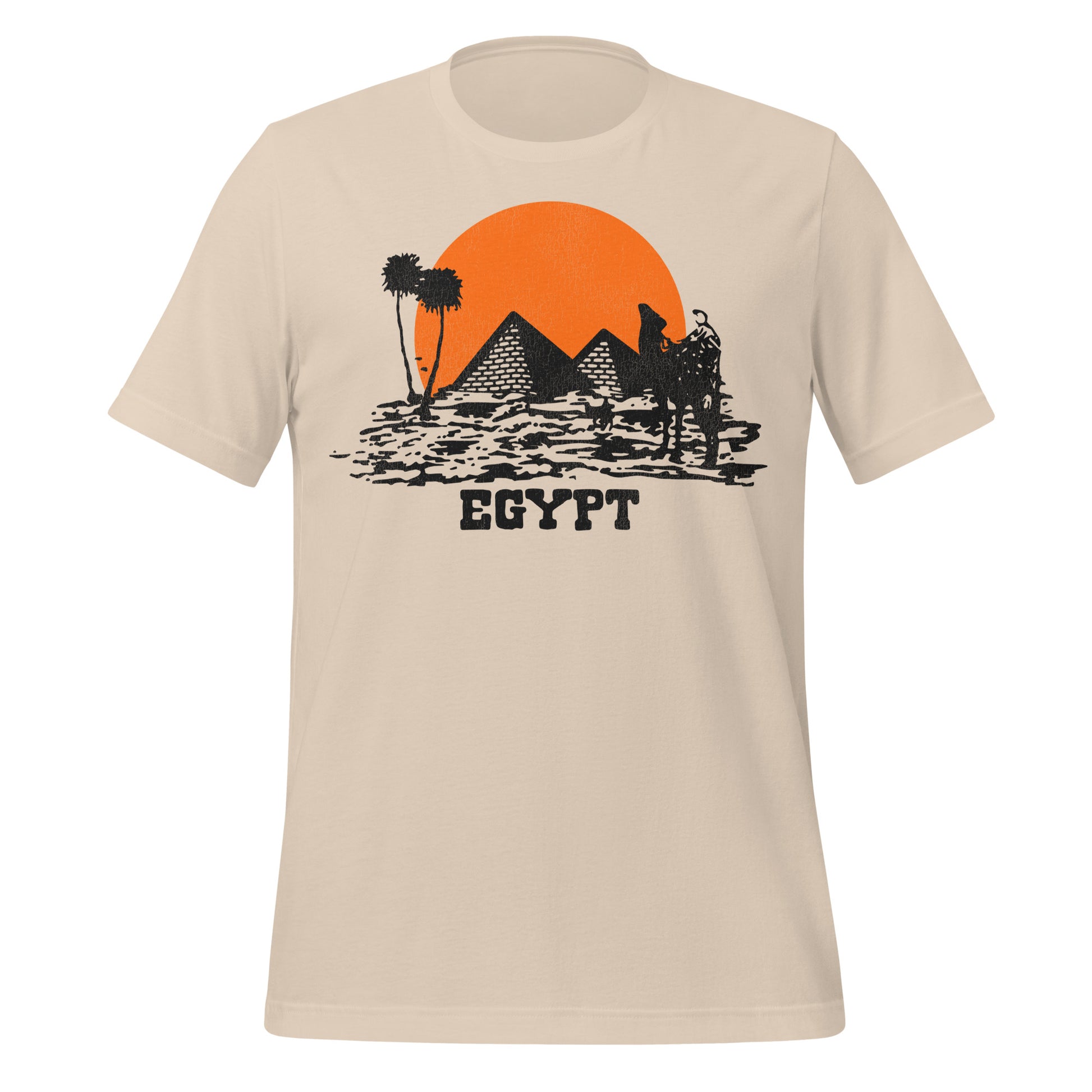 A soft cream colored retro Egypt t-shirt with an image of an orange sun setting behind the pyramids, palm trees and a camel in the distance on top of the desert. 