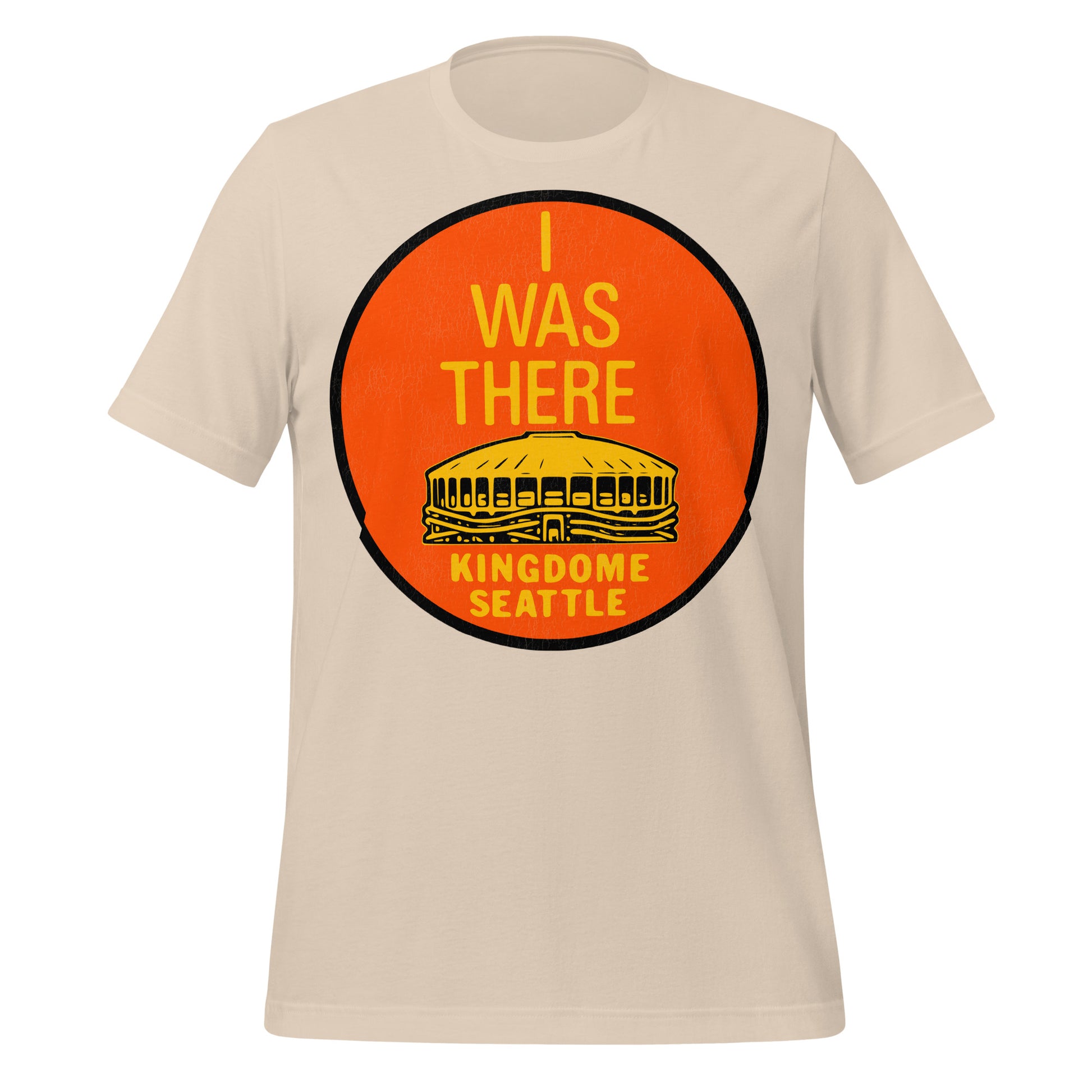 A soft cream 70s style t-shirt that says "I Was There" with an image of a stadium in yellow, the "Kingdome Seattle", where the Seattle Seahawks NFL team, Seattle SuperSonics NBA team and the Seattle Mariners MLB team played until it was demolished in 2000. Officially known as King County Stadium. 