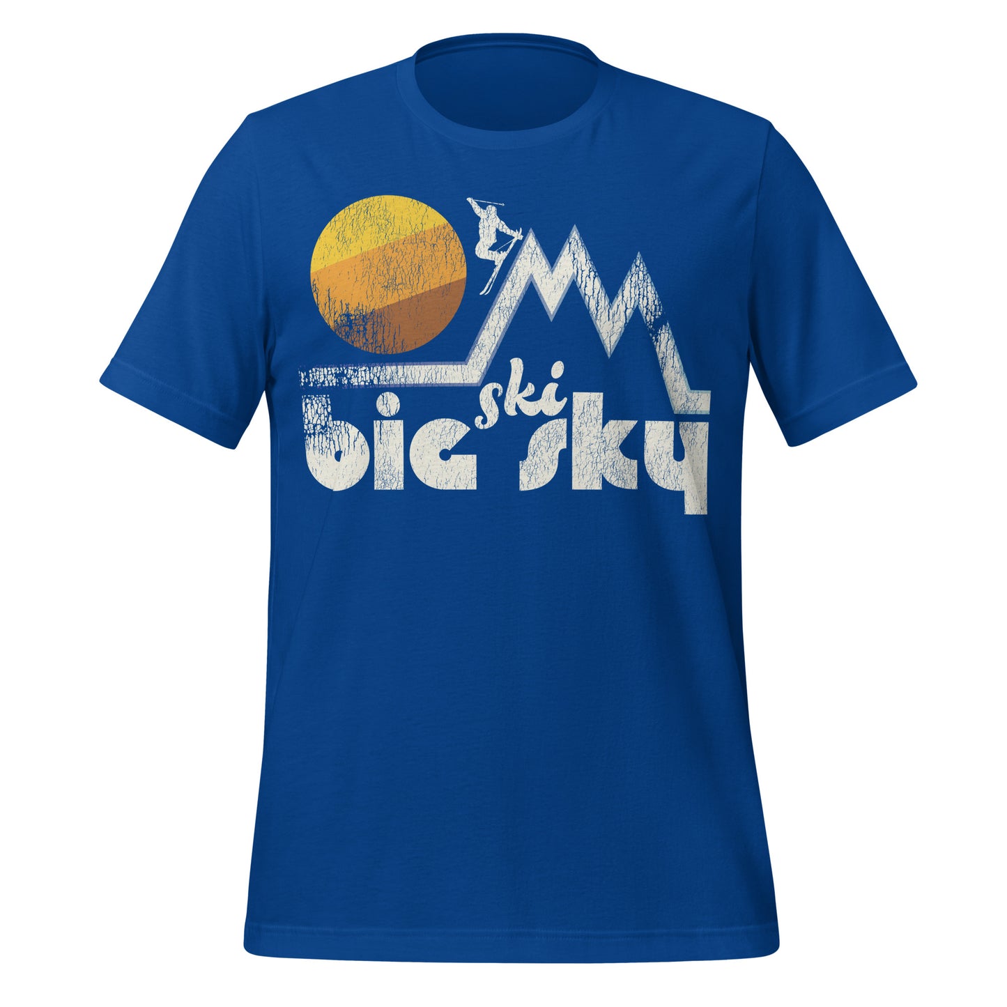 A royal blue colored travel t-shirt that says "Ski Big Sky", referencing Montana's Big Sky Resort in the Spanish Peaks. Image of a skier on a steep slope in a mountain range as the sun sets. 
