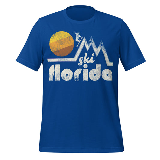 A souvenir 80s style "Ski Florida" true royal blue t-shirt. Includes image of multiple snowy mountain peaks and a skier going down one with a large sun in the distance. 
