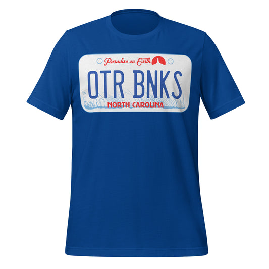 A royal blue retro style short sleeved t-shirt with the image of a license plate with letters "OTR BNKS", the words "Paradise on Earth", state "North Carolina", with a background of coastal grass and a small circular red lighthouse image. References the Netflix show and town 'Outer Banks'. 