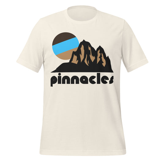 A vintage white colored souvenir 'Pinnacles' t-shirt with an image of a mountainous landscape and a brown/blue sun rising above the rock formations. In reference to California's Pinnacles National Park, famous for its brilliant hiking trails and incredible rock climbing opportunities, especially on the special rock formations known as pinnacles, as well as its famous talus caves. 