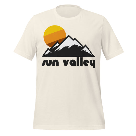 A vintage white colored "Sun Valley" retro, 70s style t-shirt that has the image of the Rocky Mountains with snow on the peaks and a yellow, brown, and orange sun rising behind. References the Sun Valley Resort in Idaho, known for its incredible vertical slopes, perfect for skiing. 