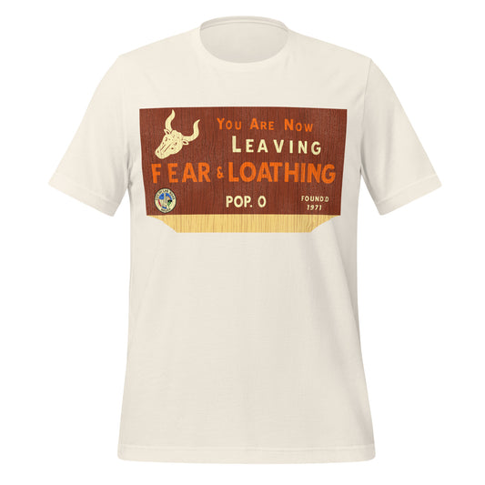 A vintage white colored travel t-shirt that says "You are Now Leaving Fear & Loathing", referencing the film Fear and Loathing in Las Vegas. Says "Pop. 0" and "Founded 1971" with the Seal of Las Vegas, saying "City of Las Vegas, Nevada" and a picture of a horned bull skull. 