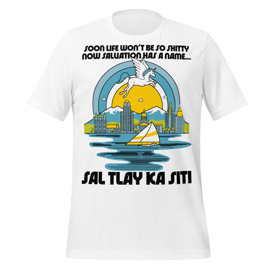 A white colored vintage t-shirt that says "Sal Tlay Ka Siti" and "Soon Life Won't Be So Shitty Now Salvation Has A Name...", which is a reference to lyrics from Nabulungi's song from the Book of Mormon musical. Image of a magic unicorn flying over blue snow covered mountains behind the Salt Lake City skyline, the Great Salt Lake with a sailboat, and a sun surrounded by blue rings, as Nabulung fantasizes about paradise.  